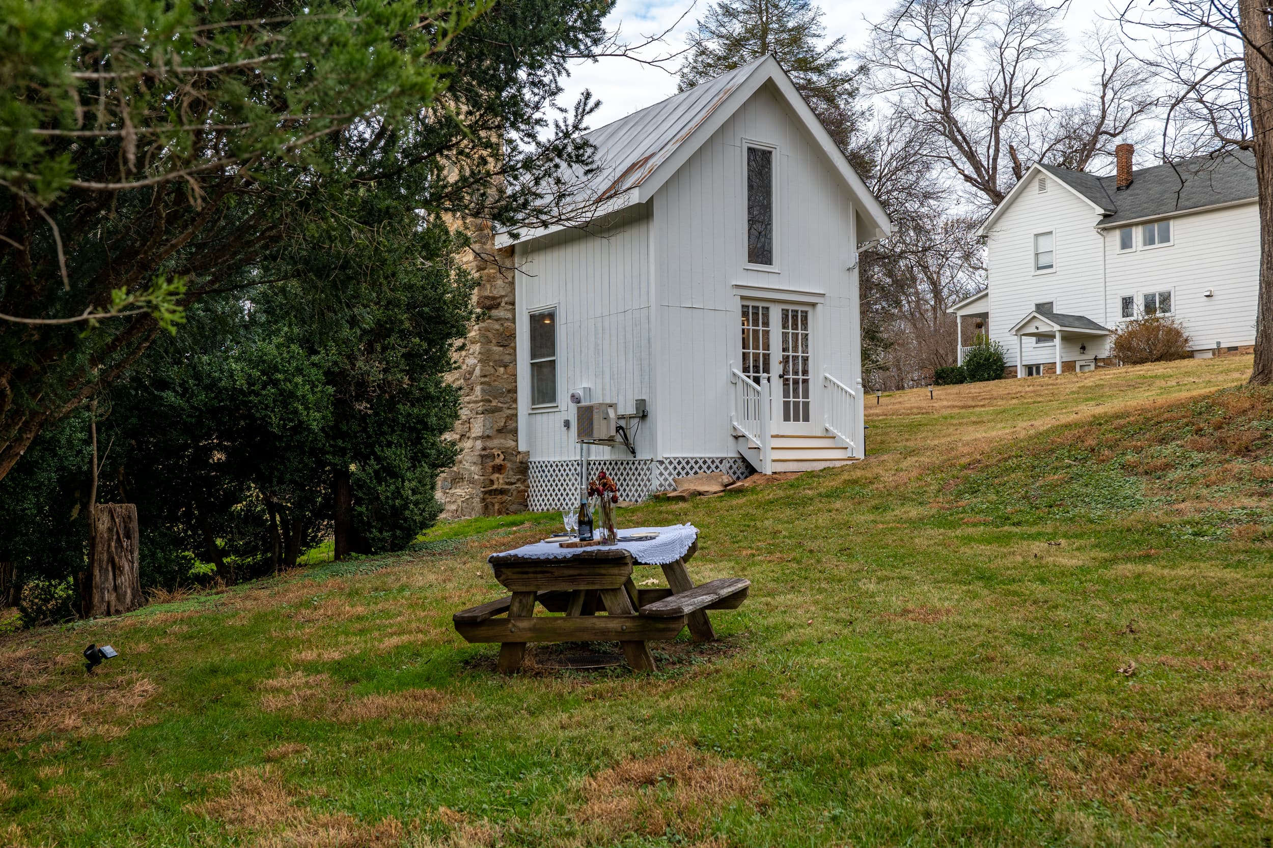 The cottage with picnic table and main farmhouse on the hill