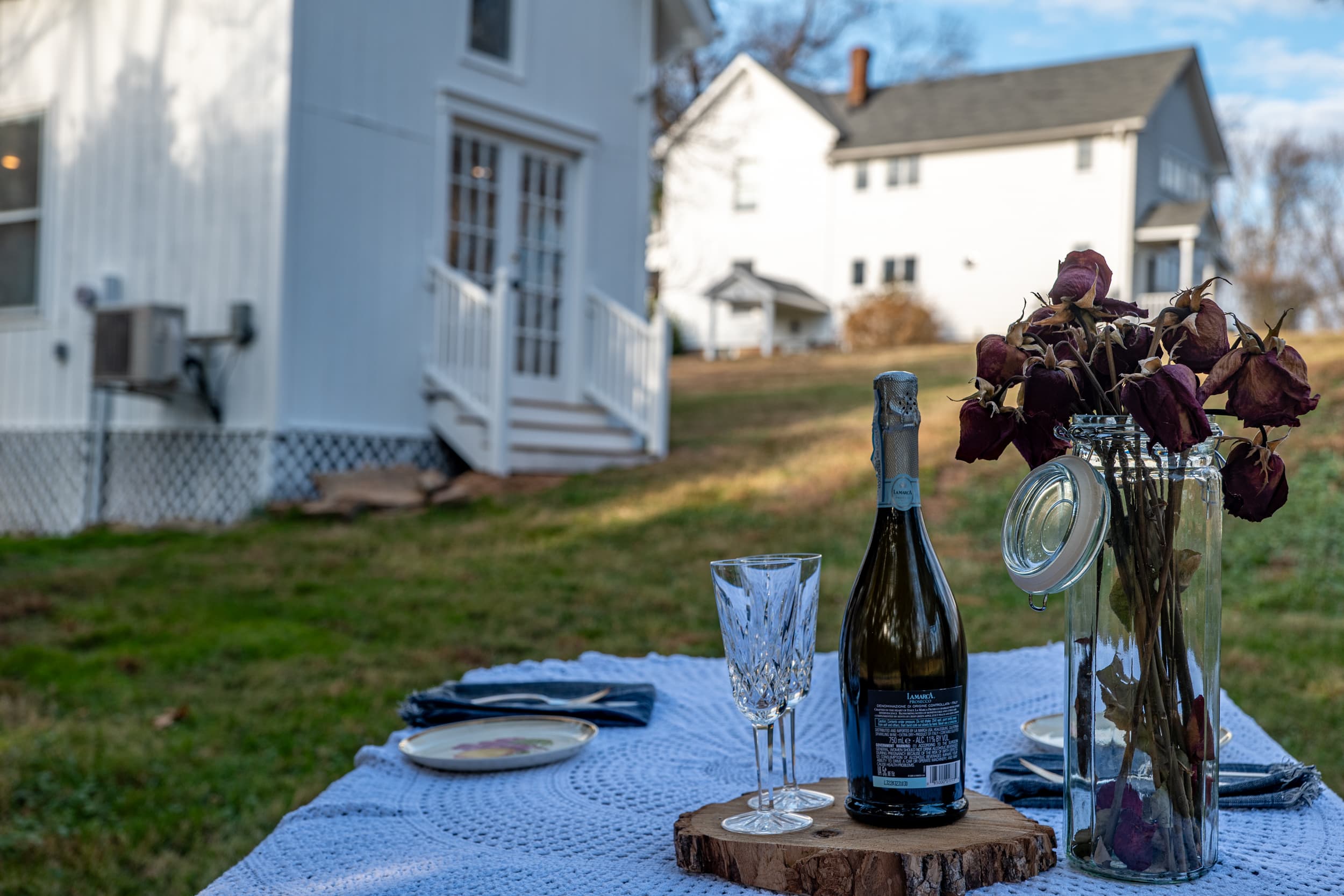 Champagne and flowers on the picnic table with the cottage behind