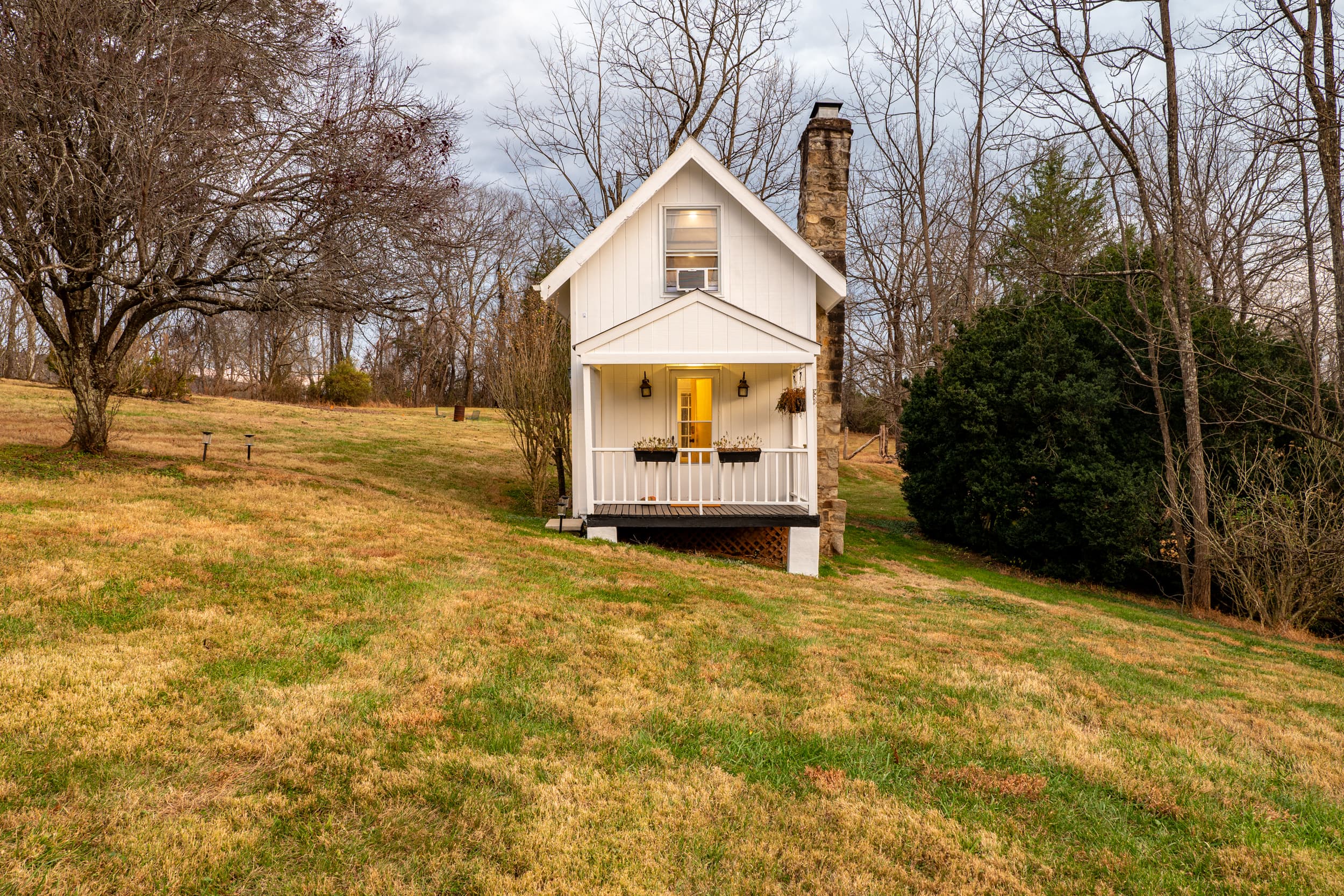The cottage head-on with stone chimney and warm glow