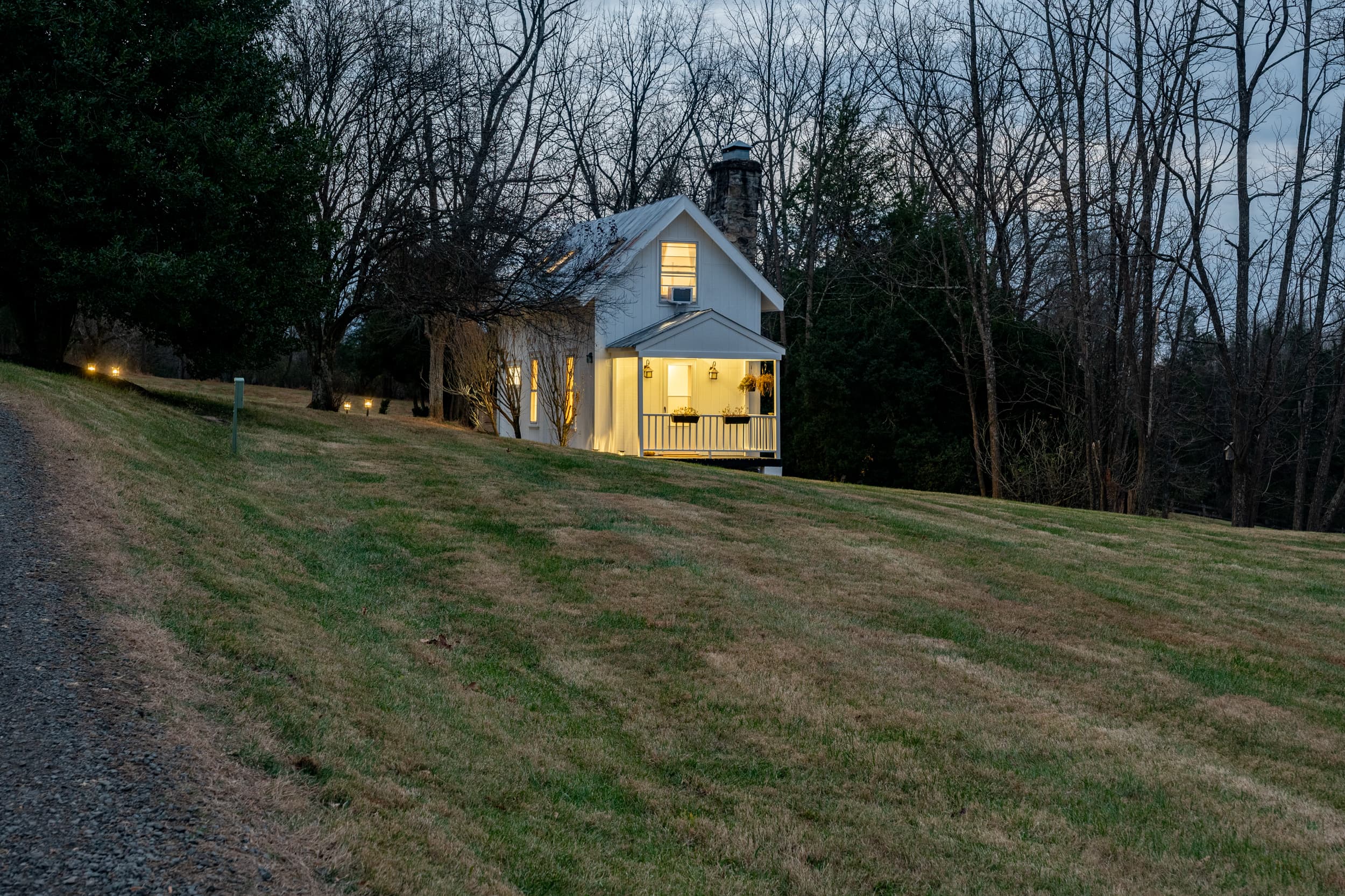 Ingleside Farm tiny home at dusk, warm light glowing from the windows